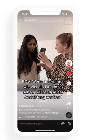 Zwei junge Frauen schauen auf ein Smartphone in einem TikTok-Video zum Thema Ausbildungsvergütung.